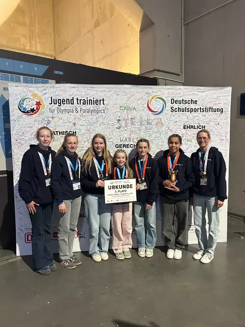 Bei der Siegerehrung vor der großen Leinwand in der Max-Schmeling-Halle v.l.: Lilly Heilandt, Co-Trainerin Lea Pauline Scholz, Patrica Pansegrau, Anni Denschstädt, Laura Claessen, Latisha Lange  und Cheftrainerin Meike Scholz.