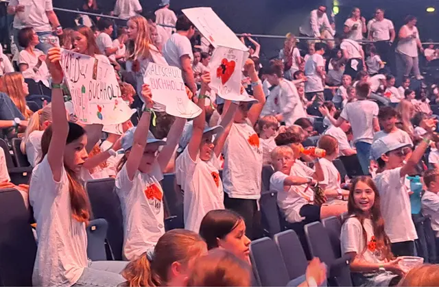  Schüler halten ihre Plakate vor dem Auftritt auf der Tribüne hoch