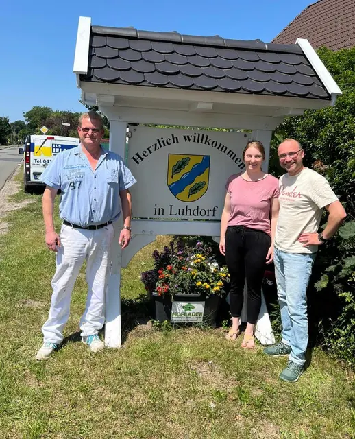 Malermeister Nils Nielsen (v. li.), Stephanie Hiller und Markus Hiller vor dem herausgeputzten Ortsschild | Foto: Luhdorf erLeben e.V.