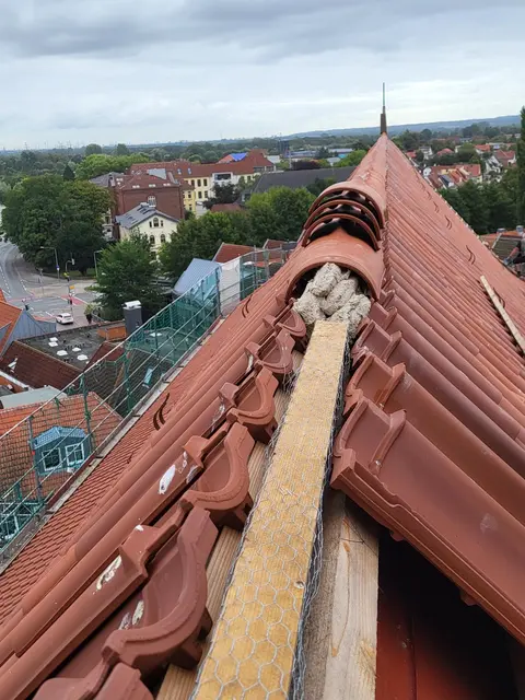 Die Ziegel auf dem First werden nach alter Handwerkskunst mit Mörtel befestigt