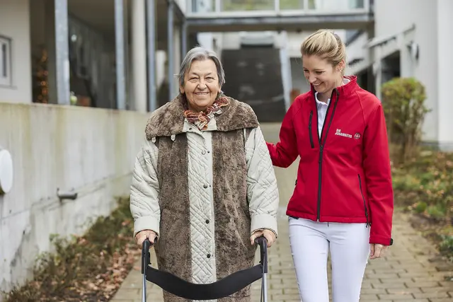 Eine Mitarbeiterin der Johanniter hilft einer pflegebedürftigen Dame  | Foto: Johanniter