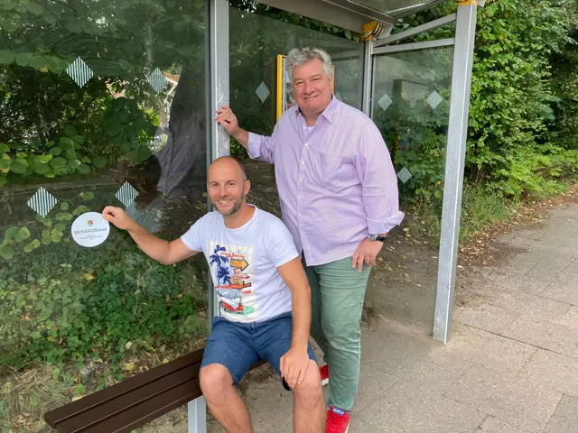 Die Wartenden, die sich über die neue Bank freuen, dürfen gern wissen, wem sie dies zu verdanken haben, deshalb klebten Tobias Münnich (li.) und Ralf Becker den bekannten Aufkleber dazu | Foto: Becker