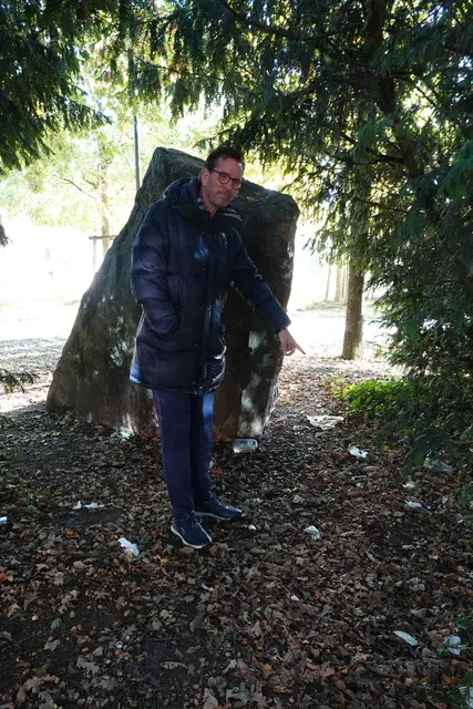 Ratsherr Bernhard Unger zeigt auf den Müll, der hinter den Bänken und einem Findling verteilt liegt | Foto: bim