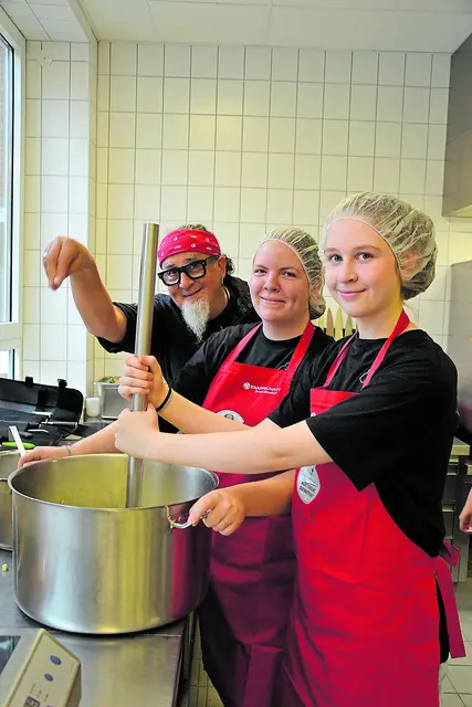 TV- und Sternekoch Stefan Marquard half den Schülerinnen Lina-Julie und Lea-Sophy beim Herstellen des Gemüse-Kartoffelpürees (v. li.) | Foto: sc