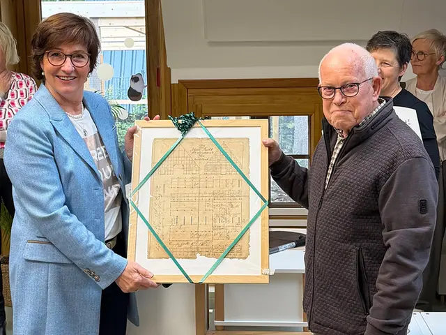 Bürgermeisterin Katja Oldenburg-Schmidt und Robert Kamprad, dessen Familie das Gebäudeensemble ehemals gehörte, mit einer gerahmten Originalbauantragsunterlage aus den 1850er Jahren, die er der Kita überreichte | Foto: Hansestadt Buxtehude