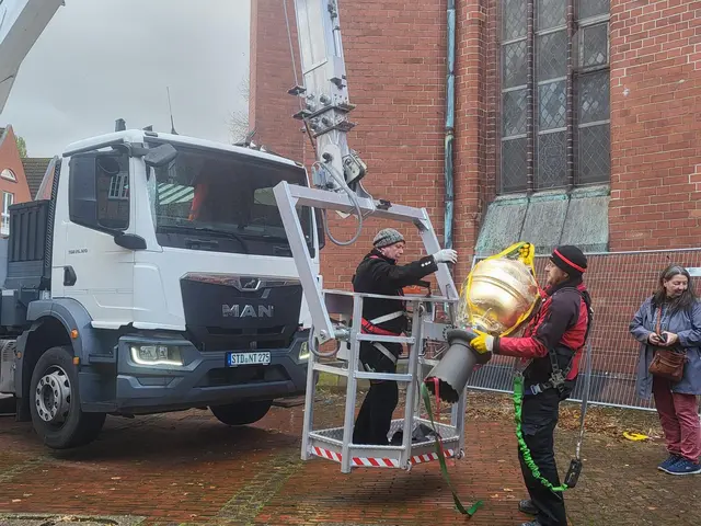Die Handwerker wuchten die rund 50 Kilogramm schwere Kugel in den Transportkorb