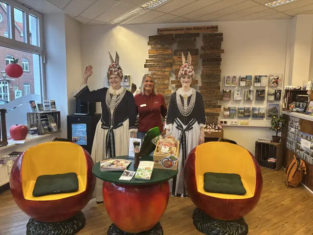 Nicole Hemmler, 46, Leiterin der Tourist Information Jork zwischen den Blütenköniginnen Aufstellern | Foto: Stefanie Schimanski