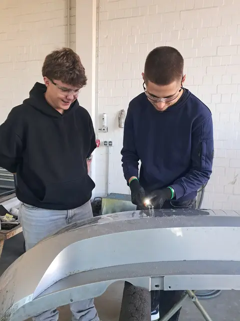 Junos Blasch und Joshua Scheffczyk bearbeiten eine kaputte Stoßstande | Foto: Anika Werner