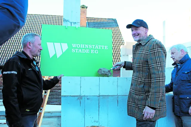 Nach der Begrüßung durch Wohnstätte-Geschäftsführer Dr. Christian Pape (kl. Foto) mauerte Architekt Torsten Wilhelmi (großes Foto Mitte) gemeinsam mit Maurerpolier Jan Eversen von der Baufirma Lindemann (li.) und Oliver Stapel von der Wohnstätte die Zeitkapsel in den Neubau ein   Fotos: sb