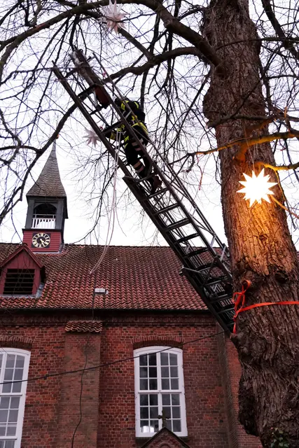 Feuerwehrmann auf der Drehleiter sichert Leucht-Stern | Foto: Rolf Hillyer-Funke/Feuerwehren SG Oldendorf-Himmelpforten