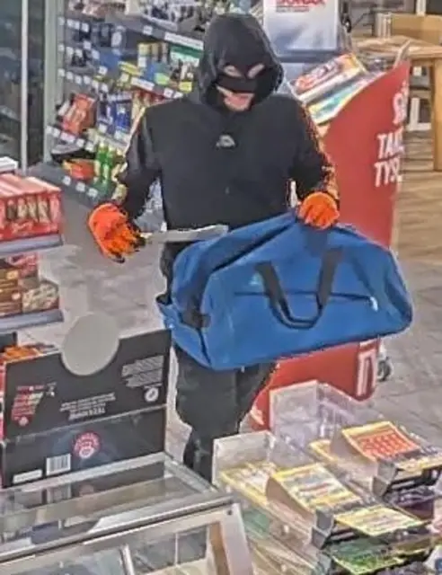 Der  maskierte Tankstellenräuber mit Messer und Tasche | Foto: Polizei