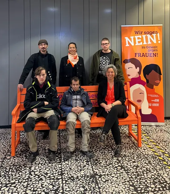 Die neue orangefarbene Bank im Kreishaus ist ein sichtbares Zeichengegen Gewalt gegen Frauen, die die Beschäftigte der Lebenshilfe, Kreisrätin Ana Cristina Bröcking (stehend, Mitte) und Gleichstellungsbeauftragte Andrea Schrag (sitzend, re.) aufgestellt haben | Foto: Landkreis Harburg