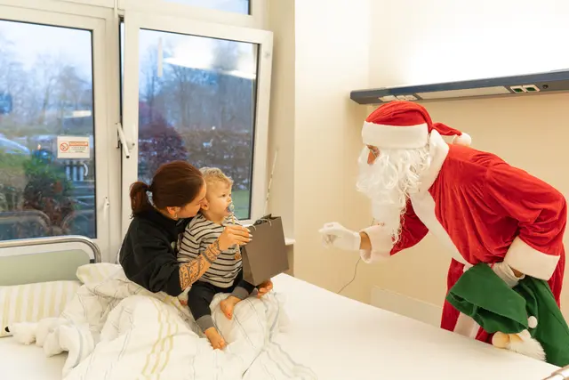 Mit großen Augen schaut der kleine Maleo den Weihnachtsmann an, als dieser in sein Zimmer kommt und ihm ein Geschenk überreicht | Foto: Elbe Kliniken / Kati Meyer-Thie�dig