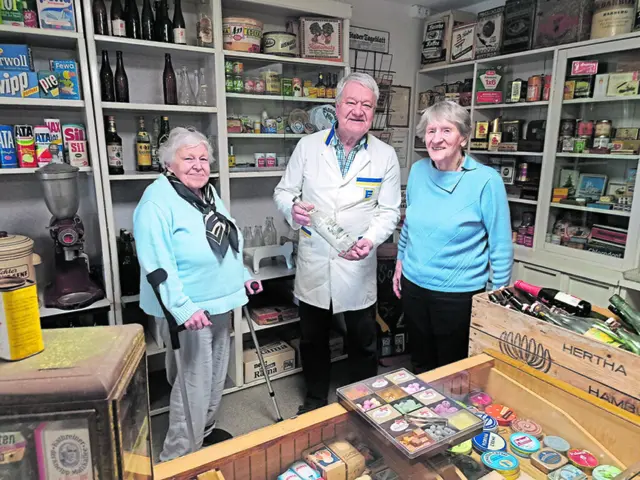 Ein Foto aus dem Kaufmannsladen der Helmster Heimatstube, aufgenommen 2023 (v.li.) Helga Wolters, Reiner Klintworth und Therese Doberitz. Reiner Klintworth war früher selbst im Lebensmitteleinzelhandel tätig, Helga Wolters und Therese Doberitz, ebenfalls ehemalige Einzelhändlerinnen, haben viel zum Interieur des Museumsladens beigetragen | Foto: Christine Klintworth