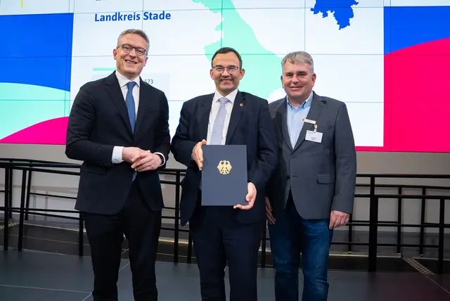 Bundesminister Dr. Karsten Wildberger (v. li.) überreicht die symbolische Förderurkunde der „Gigabitförderung 2.0“ an Thorsten Heinze, Erster Kreisrat, und Kai-Ulrich Baak, Leiter des Amtes für Wirtschaft, Verkehr und Bildung, in Berlin | Foto: Bundesministerium für Digitales und Staatsmodernisierung
