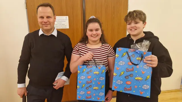Jörn Stolle (Chef der Unternehmenskommunikation von der Sparkasse) überreichte Martje (13) und Joris Fenz (11) aus Seppensen ein paar Souvenirs 