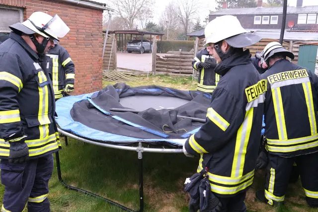 Die Feuerwehr sichert ein weggewehtes Trampolin. Der beschädigte Zaun ist im Hintergrund zu sehen. | Foto: Rolf Hillyer-Funke/Feuerwehren SG Oldendorf-Himmelpforten