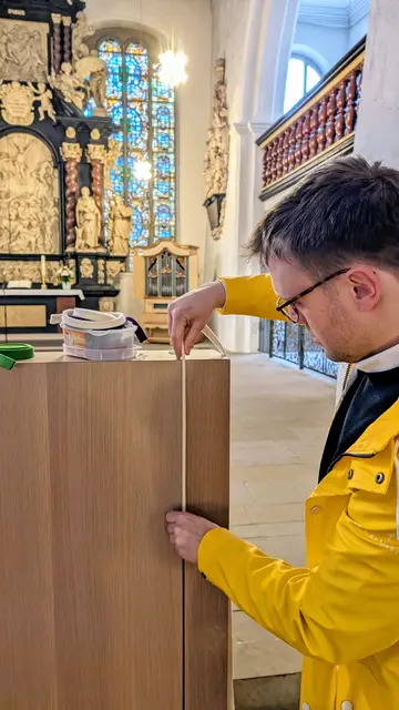 Pastor Jonas Milde zieht einen weißen Filzstreifen in den Ambo von St. Cosmae ein. Weiß ist die Farbe für hohe kirchliche Feste wie Ostern | Foto: jd