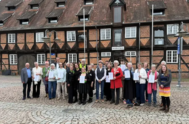 Zur Eröffnungsfeier versammeln sich die Gewinner und Gewinnerinnen des Kultursommerpreises 2026 unter dem Motto „Neue Wege“ vor dem Museum im Marstall mit Andreas Sommer, Vorstandsvorsitzender der Sparkasse Harburg-Buxtehude, (5. v. l. hinten), Landrat Rainer Rempe (2. v. r.) und Marie-Nathalie Schrötke, Projektleiterin Kulturlandkreis Harburg, (rechts) | Foto: FLMK