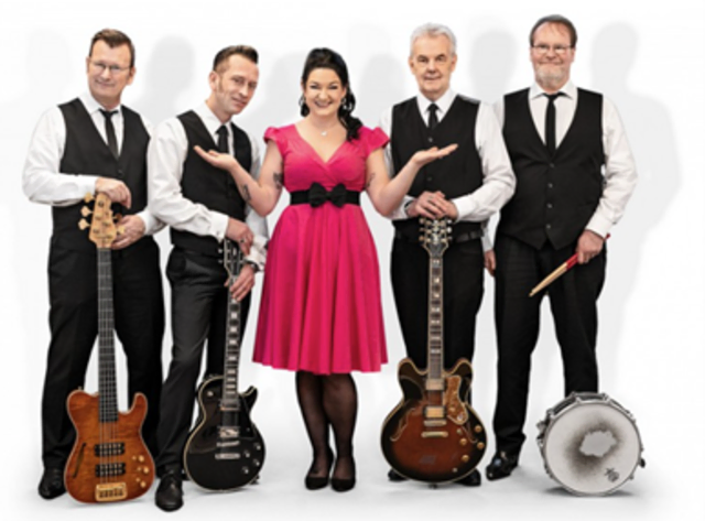 Fünf Menschen sind auf dem Bild zu sehen. In der Mitte steht eine Frau in einem pinken Kleid, links und rechts neben ihr jeweils zwei Männer mit Instrumenten