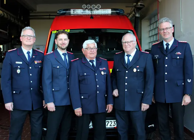 Fünf Feuerwehrmänner vor einem Mannschaftswagen der Feuerwehr