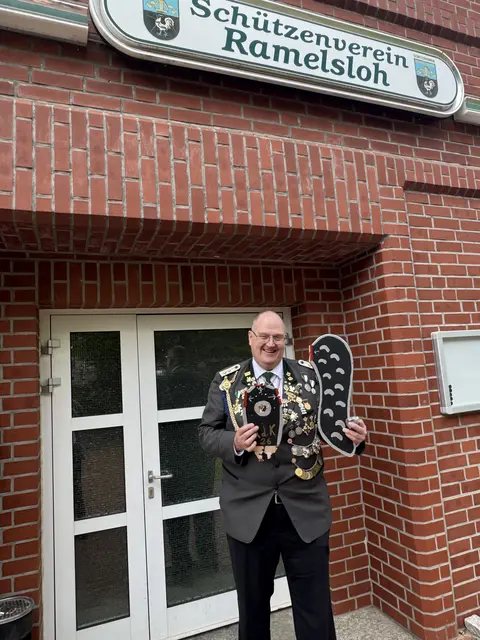 Ein Mann steht vor dem Eingang und hält zwei Holzteile vor sich