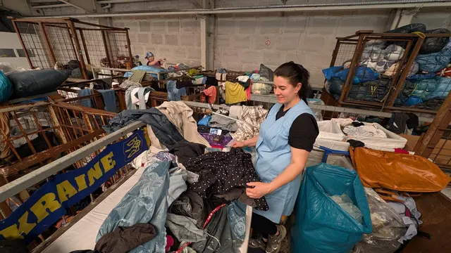 Eine Mitarbeiterin hat einen Altkleidersack geöffnet. Sie begutachtet mit geschultem Blick die Ware | Foto: jd