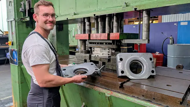 Nathanael Bösch ist stellvertretender Betriebsleiter. Er hält ein Bauteil für Hallenkräne in der Hand. Der acht Millimeter dicke Stahl wird zunächst mit einem Druck von 650 Tonnen umgeformt. Danach werden noch vier Löcher ausgestanzt | Foto: jd