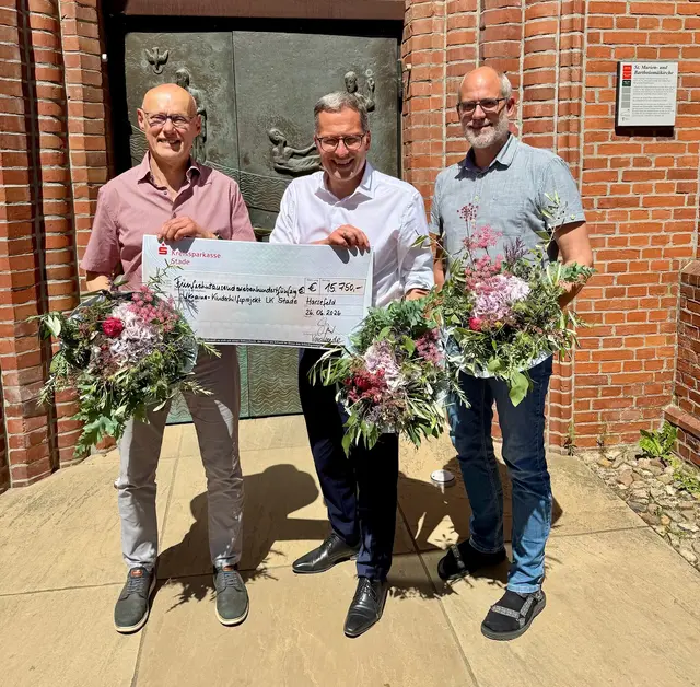 Kirchenvorsteher Hermann Fitschen (li.) und Diakon Björn Reinkemeier (re.) übergeben einen symbolischen Scheck über 15.750 Euro an Landrat Kai Seefried. Die Spenden werden für die Ukraine-Kinderfreizeit eingesetzt. | Foto: Landkreis Stade/Florian Obst