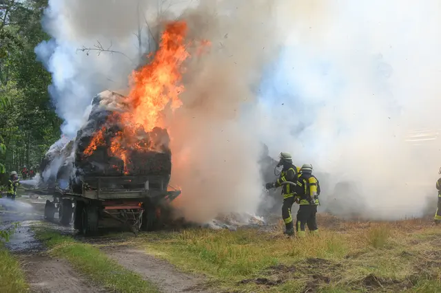 Die Feuerwehr löscht die auf dem Trecker-Anhänger aus bislang ungeklärter Ursache brennenden Stroh-Rundballen | Foto: Mathias Wille
