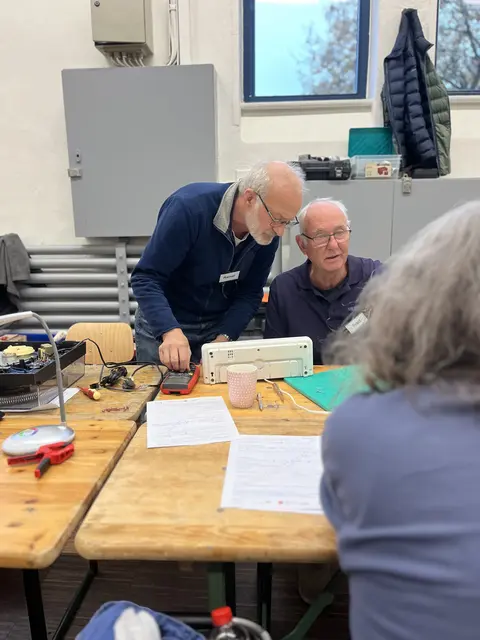 Rainer Wollrab und Fred Mordhorst unterstützen als ehrenamtliche Repairler eine Besucherin bei der Reparatur 
