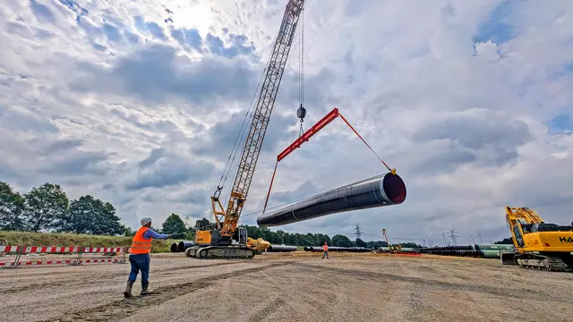 Ein rund 15 Tonnen schweres Stahlrohr für die Erdgasleitung wird mittels eines Seilkrans quer über den Lagerplatz in Deinste transportiert | Foto: jd