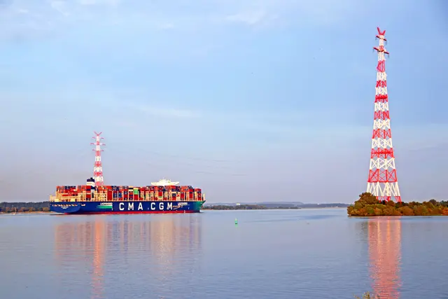 Die CMA CGM Rivoli schiebt sich zwischen den beiden hohen Masten der Strom-Elbquerung bei Lühesand durch das Fahrwasser | Foto: jd