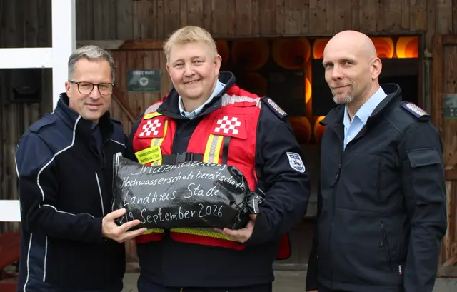 Landrat Kai Seefried (v. li.) übergibt Bereitschaftsführer Henning Stegmann und dessen Stellvertreter Nils Carstensen einen symbolischen Sandsack | Foto: Stefan Braun/Feuerwehr