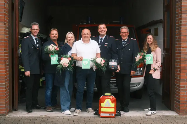 Gemeinsam für schnelle Hilfe im Notfall: Vertreter der Feuerwehr und des Fördervereins mit Unterstützern der neuen AED-Gruppe am Gerätehaus in Gräpel | Foto: Jaspar Holst/Feuerwehr Gräpel