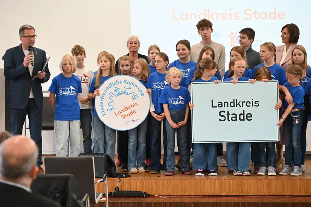 Landrat Kai Seefried und die Buxtehuder Stieglitze präsentieren das Siegel „Kinderfreundliche Kommune“ für den Landkreis Stade. Im Hintergrund: Vereinsgründerin Dr. Heide-Rose Brückner, Kreisschülerratssprecher Hauke Ilsemann und Elias Scherzinger sowie die Parlamentarische Staatssekretärin Mareike Wulf | Foto: Landkreis Stade / Daniel Beneke