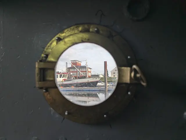 Blick auf Hafen und Speicher durch das Bullauge im Maschinenraum des Frachtschiffes "Ilmenau" | Foto: Jan Filter