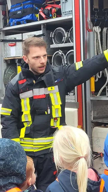 Gruppenführer Lucas Belser erklärt den Kindern die Arbeit der Feuerwehr 