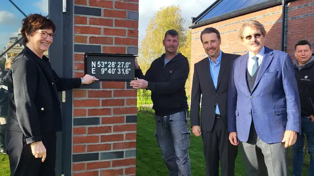 Katja Oldenburg-Schmidt, André Dittmer, Dirk und Andreas Viebrock mit dem Schild, auf dem die Koordinationsdaten stehen und mit dem das Loch für die Zeitkapsel verschlossen wird